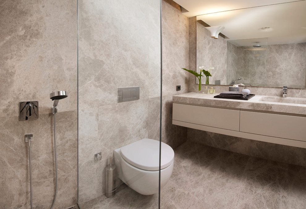 Inredning av ett modernt mellanstort grå grått en-suite badrum, med släta luckor, grå skåp, en dusch i en alkov, en vägghängd toalettstol, grå kakel, keramikplattor, grå väggar, klinkergolv i porslin, ett undermonterad handfat, marmorbänkskiva, grått golv och dusch med gångjärnsdörr
