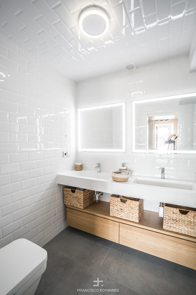 Inspiration for a contemporary bathroom in Other with white cabinets, a walk-in shower, a wall mounted toilet, white tiles, metro tiles, white walls, porcelain flooring, an integrated sink, engineered stone worktops and grey floors.