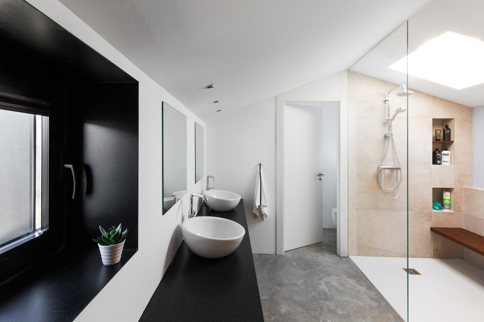Пример оригинального дизайна: большая главная ванная комната в современном стиле с плоскими фасадами, душем без бортиков, бежевой плиткой, керамической плиткой, белыми стенами, бетонным полом, настольной раковиной, столешницей из гранита, серым полом, черной столешницей и открытым душем