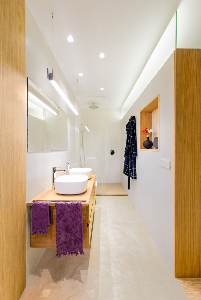 Свежая идея для дизайна: большая главная ванная комната в стиле модернизм с плоскими фасадами, светлыми деревянными фасадами, открытым душем, белой плиткой, цементной плиткой, белыми стенами, бетонным полом, настольной раковиной, столешницей из дерева, коричневым полом, открытым душем и коричневой столешницей - отличное фото интерьера