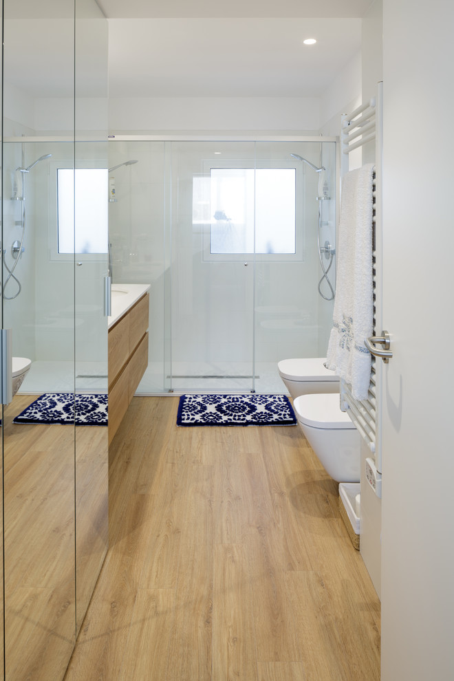 Exemple d'une salle de bain moderne en bois brun avec un placard à porte plane, WC suspendus, des carreaux de céramique, un mur blanc, un sol en bois brun, un lavabo encastré, un plan de toilette en quartz modifié, un plan de toilette blanc, un carrelage blanc, un sol beige et une cabine de douche à porte coulissante.