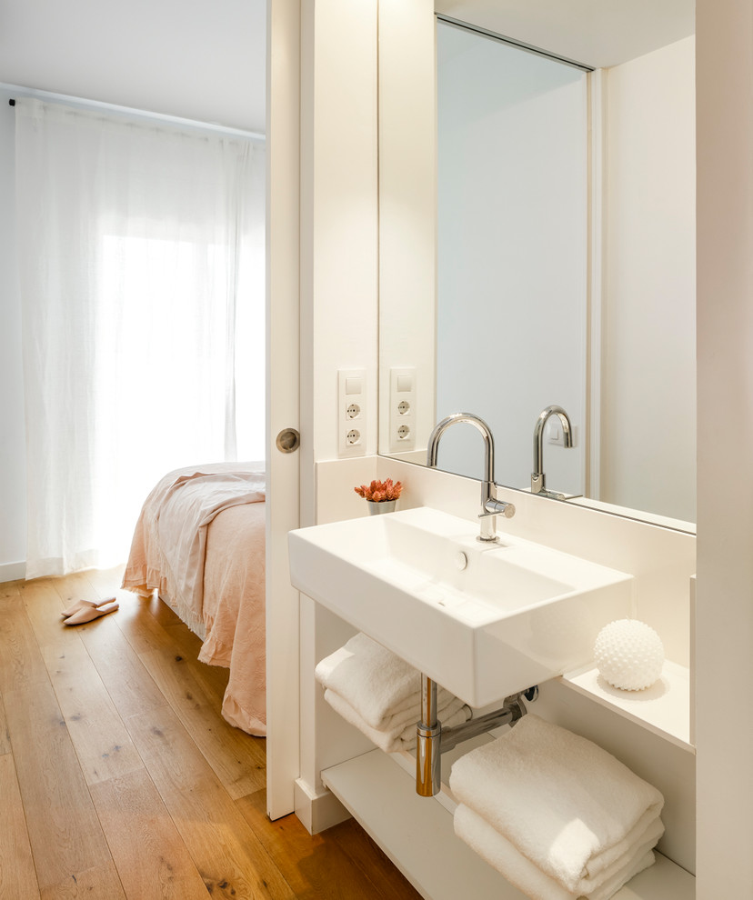 Foto på ett medelhavsstil vit en-suite badrum, med en kantlös dusch, en toalettstol med hel cisternkåpa, vita väggar, mellanmörkt trägolv, ett fristående handfat, marmorbänkskiva och dusch med skjutdörr
