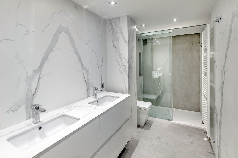 Inspiration for a mid-sized transitional 3/4 walk-in shower remodel in Madrid with flat-panel cabinets, white cabinets, a wall-mount toilet, white walls and an integrated sink