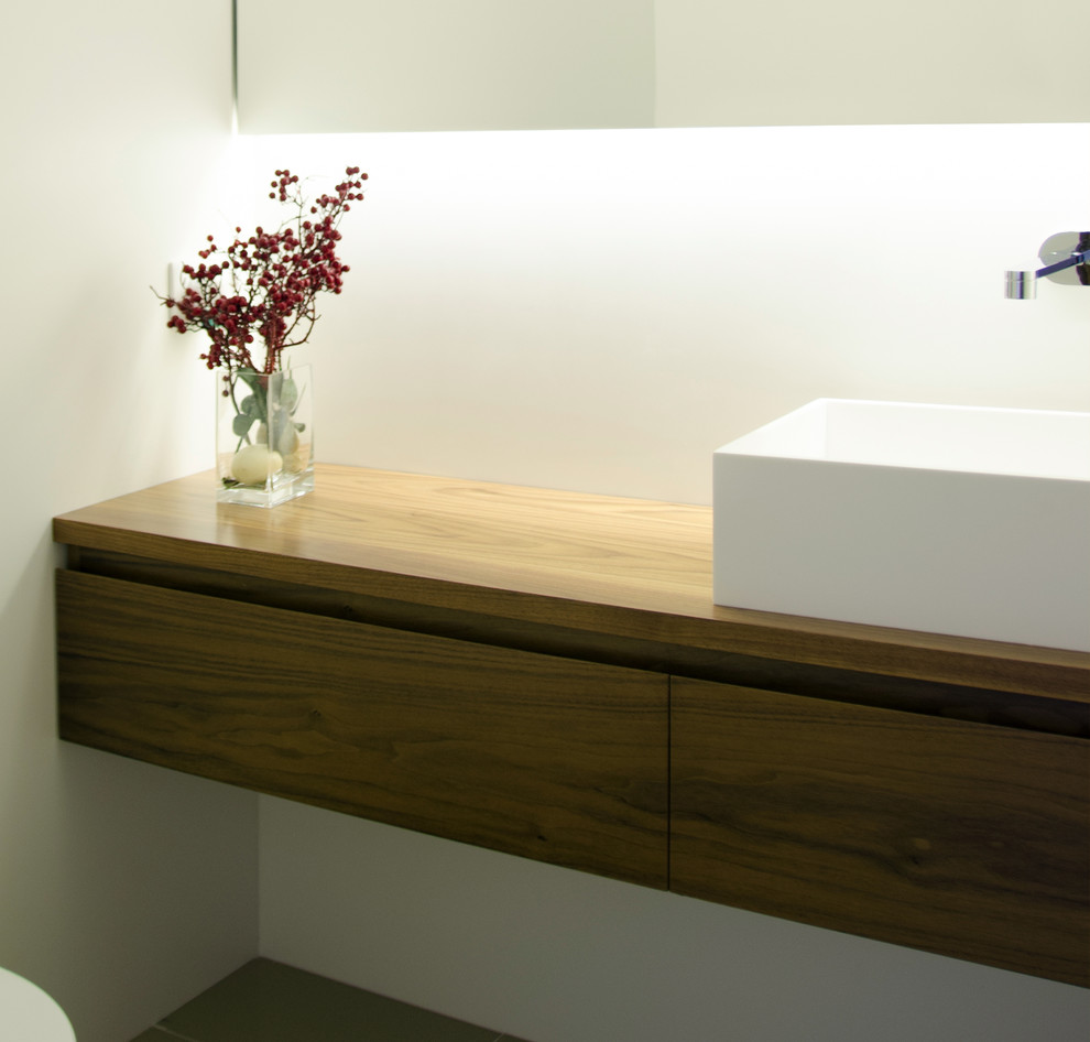 Idee per una stanza da bagno design di medie dimensioni con consolle stile comò, ante in legno scuro, lavabo a bacinella e top in legno