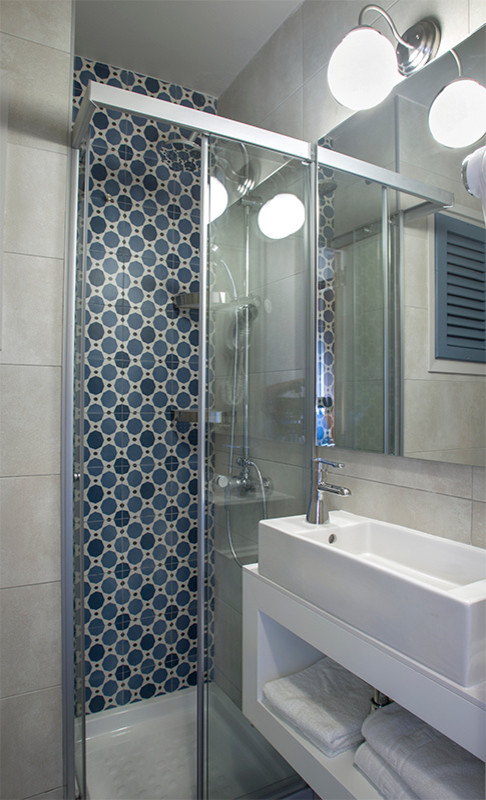 Small mediterranean shower room bathroom in Barcelona with open cabinets, white cabinets, a corner shower, a one-piece toilet, multi-coloured tiles, ceramic tiles, multi-coloured walls, vinyl flooring, a vessel sink and engineered stone worktops.