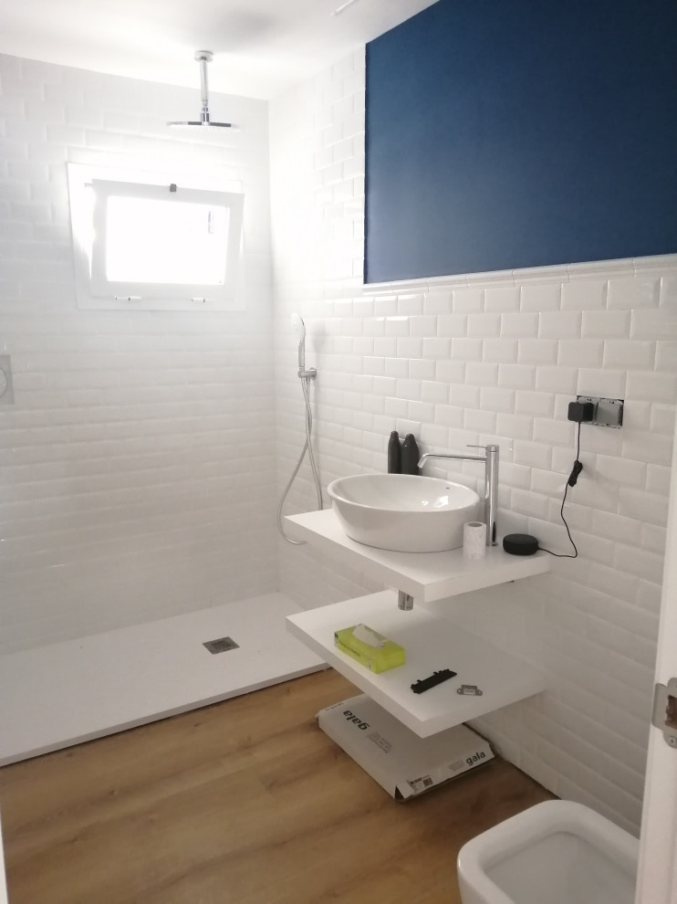 Exempel på ett litet vit vitt badrum med dusch, med en kantlös dusch, vit kakel, porslinskakel, blå väggar, laminatgolv, ett fristående handfat och laminatbänkskiva