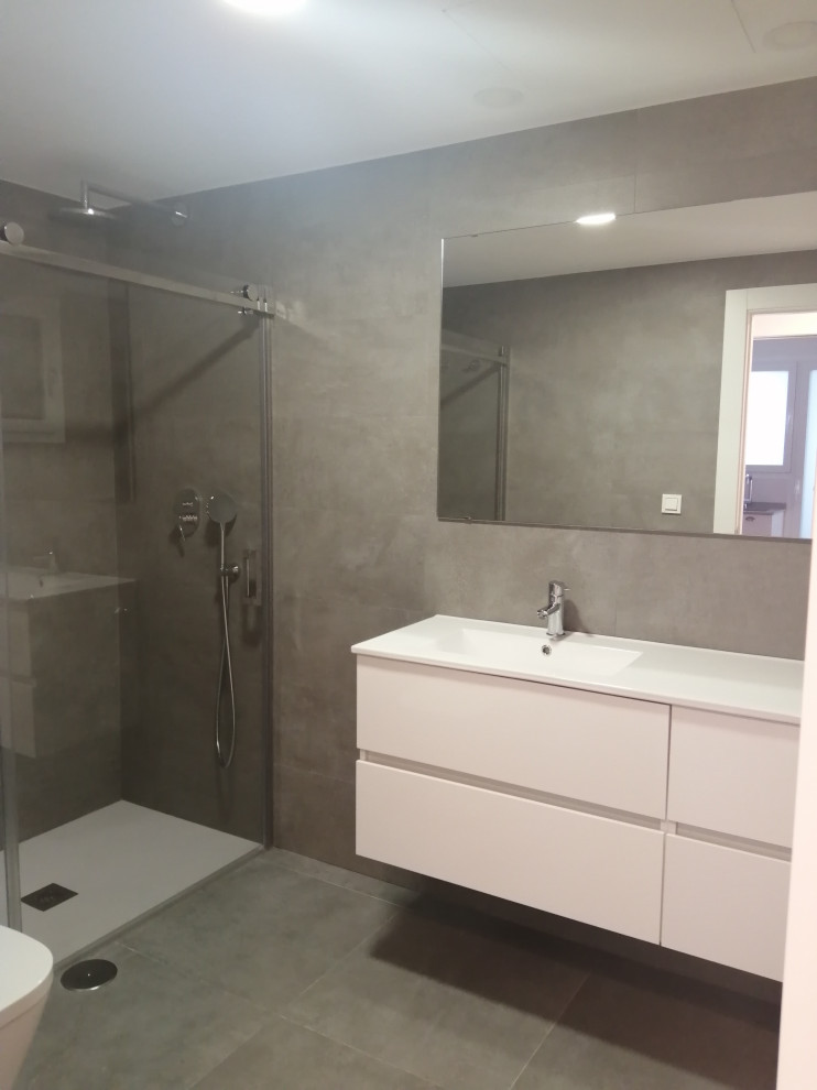 Inspiration för ett stort vit vitt en-suite badrum, med en kantlös dusch, grå kakel, porslinskakel, grå väggar, klinkergolv i porslin, ett väggmonterat handfat, bänkskiva i akrylsten, grått golv och dusch med skjutdörr