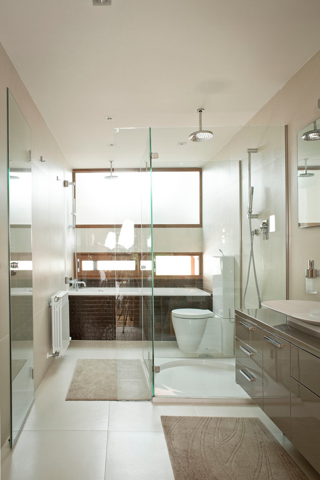 На фото: большая главная ванная комната в современном стиле с плоскими фасадами, серыми фасадами, ванной в нише, открытым душем, раздельным унитазом, керамической плиткой, бежевыми стенами, полом из керамической плитки и настольной раковиной