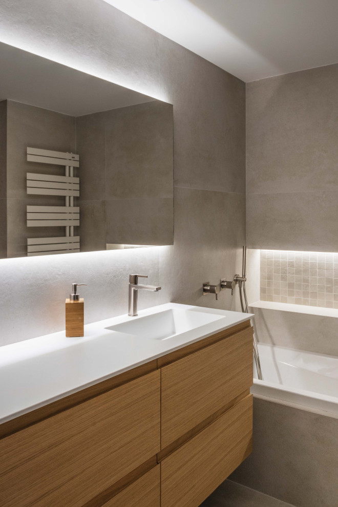 Inspiration for a medium sized modern ensuite bathroom in Valencia with freestanding cabinets, light wood cabinets, an alcove bath, a one-piece toilet, beige tiles, ceramic tiles, beige walls, ceramic flooring, an integrated sink, beige floors, an open shower, white worktops, an enclosed toilet, a single sink and a built in vanity unit.