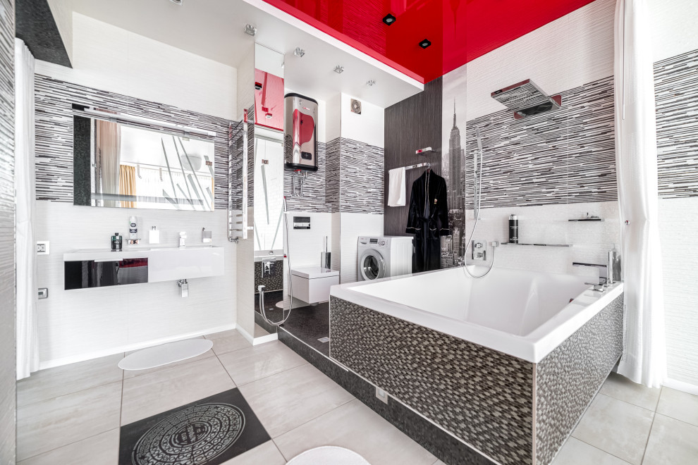 Modernes Badezimmer mit Eckbadewanne, Duschbadewanne, Wandtoilette, schwarz-weißen Fliesen, grauem Boden, Duschvorhang-Duschabtrennung, weißer Waschtischplatte, Wäscheaufbewahrung, Einzelwaschbecken und schwebendem Waschtisch
