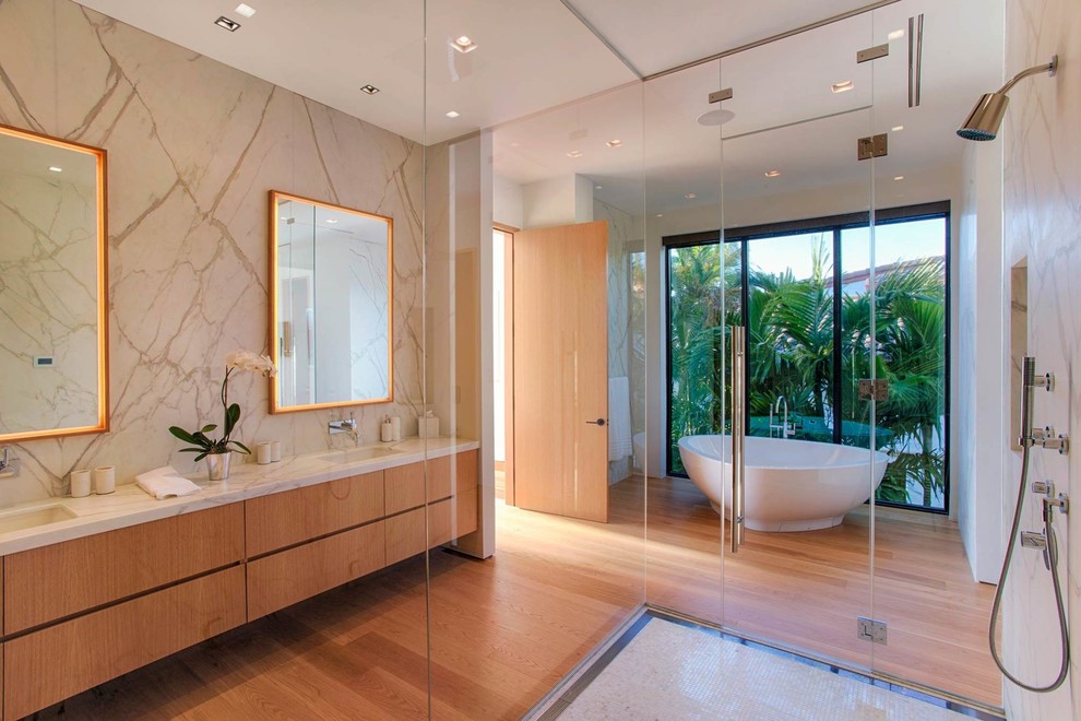 Design ideas for an expansive contemporary ensuite bathroom with flat-panel cabinets, a freestanding bath, a built-in shower, medium hardwood flooring, an integrated sink, engineered stone worktops, a hinged door, white worktops, medium wood cabinets, beige walls and brown floors.
