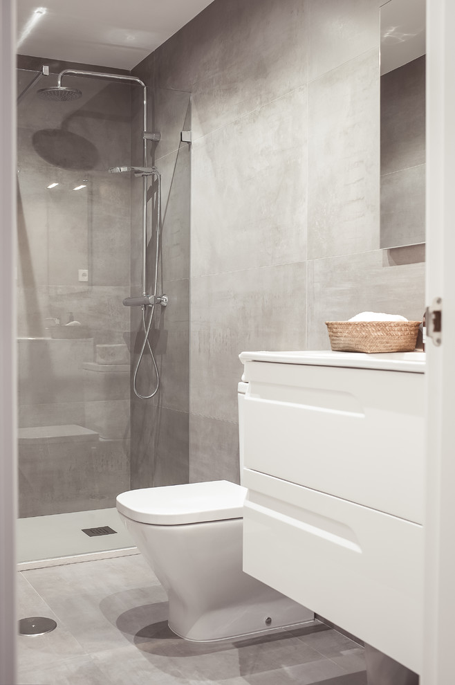 Immagine di una piccola stanza da bagno con doccia moderna con ante lisce, ante bianche, doccia a filo pavimento, WC a due pezzi, pareti grigie, lavabo integrato e porta doccia a battente