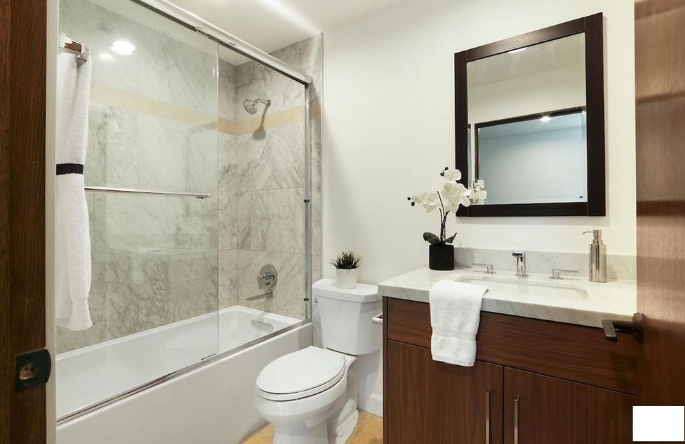 Стильный дизайн: маленькая ванная комната в стиле модернизм с фасадами островного типа, коричневыми фасадами, ванной в нише, душем над ванной, унитазом-моноблоком, бежевой плиткой, керамогранитной плиткой, белыми стенами, полом из керамической плитки, душевой кабиной, раковиной с несколькими смесителями, столешницей из искусственного кварца, бежевым полом, душем с раздвижными дверями и разноцветной столешницей для на участке и в саду - последний тренд