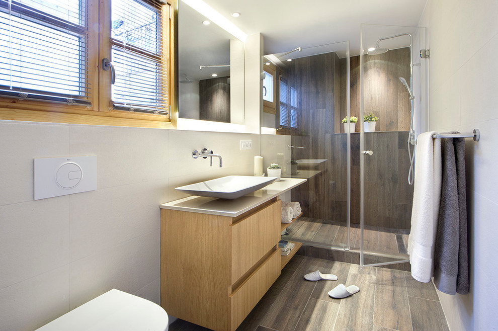 Mittelgroßes Modernes Duschbad mit flächenbündigen Schrankfronten, hellbraunen Holzschränken, Duschnische, Wandtoilette und Aufsatzwaschbecken in Madrid