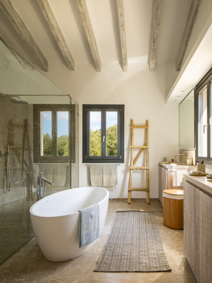 Inredning av ett medelhavsstil beige beige en-suite badrum, med släta luckor, skåp i ljust trä, ett fristående badkar, en kantlös dusch, grå kakel, vita väggar, brunt golv och dusch med gångjärnsdörr