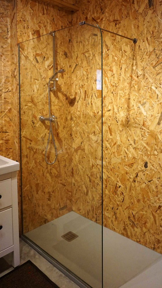 Industriell inredning av ett litet badrum med dusch, med en kantlös dusch, bruna väggar och ljust trägolv