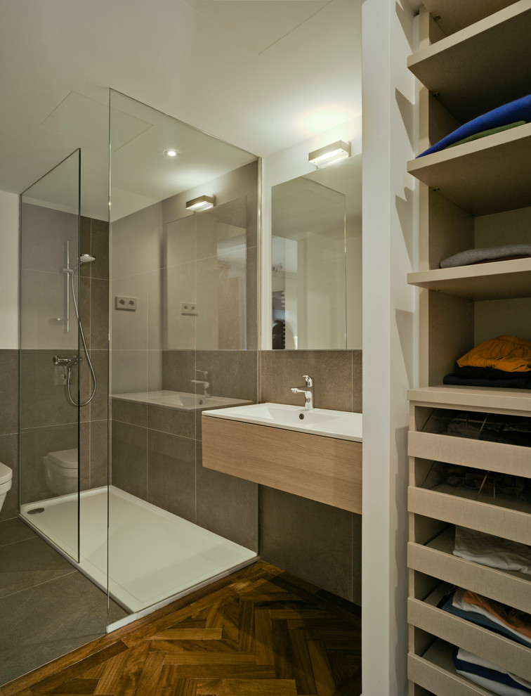 Свежая идея для дизайна: ванная комната в современном стиле с плоскими фасадами, светлыми деревянными фасадами, угловым душем, серой плиткой, темным паркетным полом, накладной раковиной и открытым душем - отличное фото интерьера