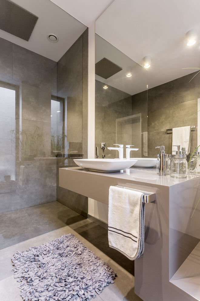 На фото: ванная комната в стиле модернизм с душем без бортиков, серой плиткой, белыми стенами, настольной раковиной, серым полом и серой столешницей с