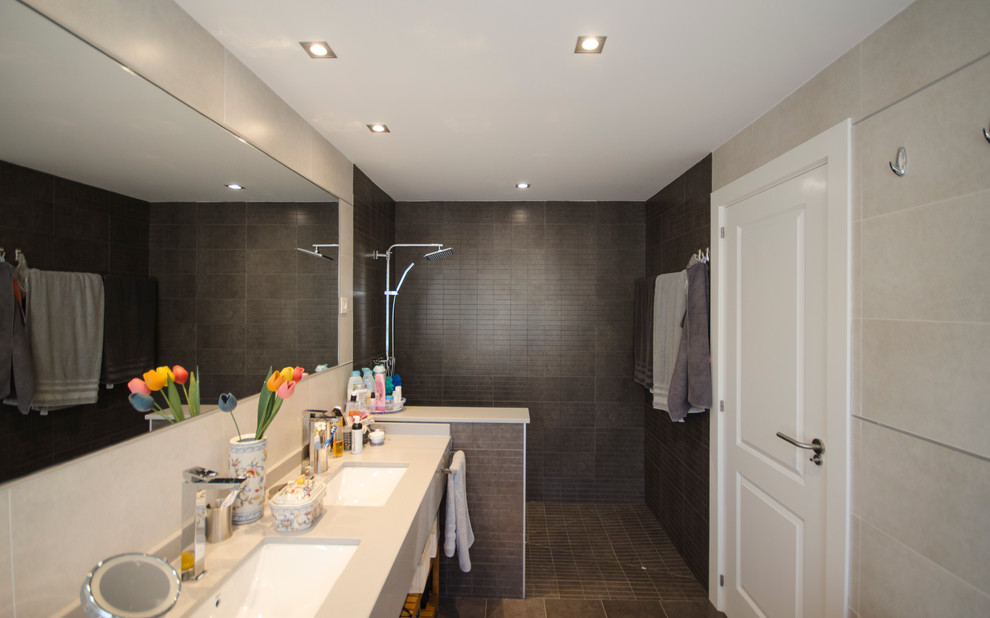 Modelo de cuarto de baño principal actual de tamaño medio con armarios abiertos, ducha abierta, paredes beige y lavabo bajoencimera