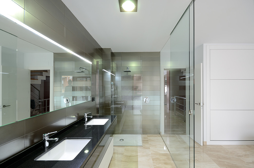 Bild på ett stort funkis badrum med dusch, med släta luckor, vita skåp, en hörndusch, grå kakel, keramikplattor, grå väggar, travertin golv, ett undermonterad handfat och bänkskiva i akrylsten