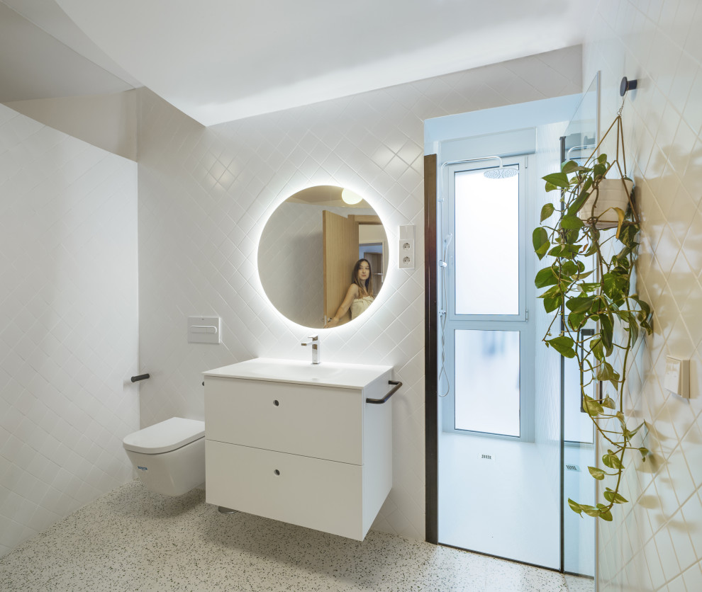 Esempio di una stanza da bagno con doccia design di medie dimensioni con ante lisce, ante bianche, WC sospeso, piastrelle bianche, piastrelle in gres porcellanato, pavimento alla veneziana, lavabo integrato, pavimento grigio e top bianco