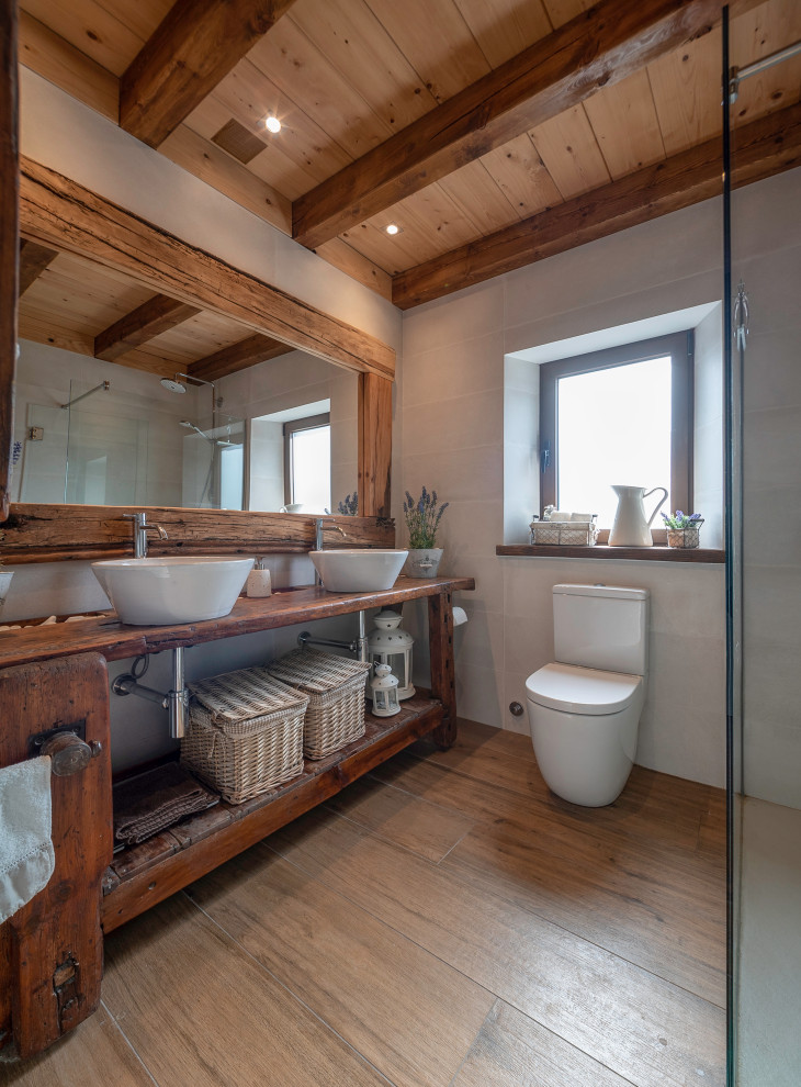 Farmhouse bathroom in Barcelona with open cabinets, dark wood cabinets, white tiles, white walls, medium hardwood flooring, a vessel sink, wooden worktops, brown floors, brown worktops, double sinks, a freestanding vanity unit, exposed beams, a vaulted ceiling and a wood ceiling.