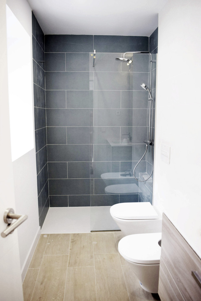 Idéer för att renovera ett mellanstort funkis vit vitt en-suite badrum, med luckor med upphöjd panel, skåp i mellenmörkt trä, en kantlös dusch, en bidé, vit kakel, keramikplattor, vita väggar, klinkergolv i keramik, ett väggmonterat handfat, kaklad bänkskiva och dusch med gångjärnsdörr