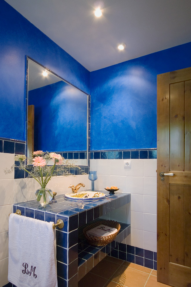 Photo of a medium sized beach style bathroom in Other with a built-in sink, open cabinets, blue cabinets, tiled worktops, blue tiles, blue walls, ceramic tiles and blue worktops.