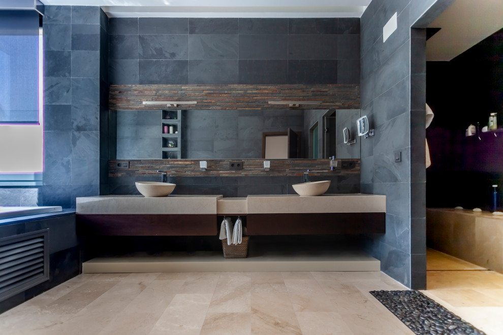 На фото: ванная комната в современном стиле с плоскими фасадами, темными деревянными фасадами, синей плиткой, черными стенами, настольной раковиной, бежевым полом и серой столешницей