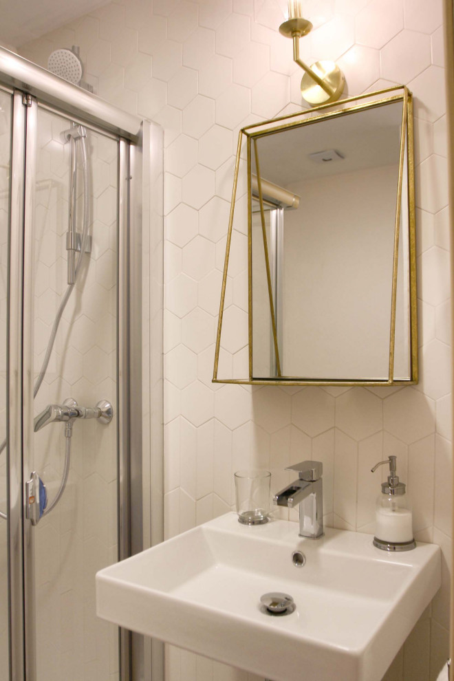 Bild på ett litet eklektiskt vit vitt badrum, med vita skåp, en hörndusch, ett urinoar, vit kakel, keramikplattor, vita väggar, ljust trägolv, ett väggmonterat handfat och dusch med gångjärnsdörr