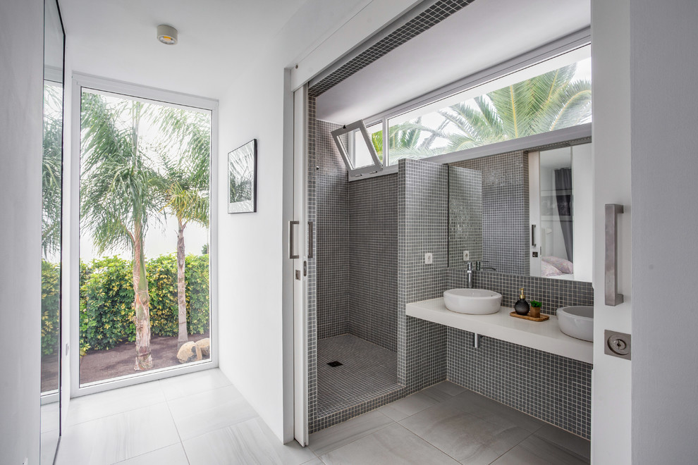Exemple d'une salle de bain tendance avec une douche d'angle, un carrelage gris, mosaïque, un mur blanc, une vasque, un sol gris, aucune cabine et un plan de toilette blanc.