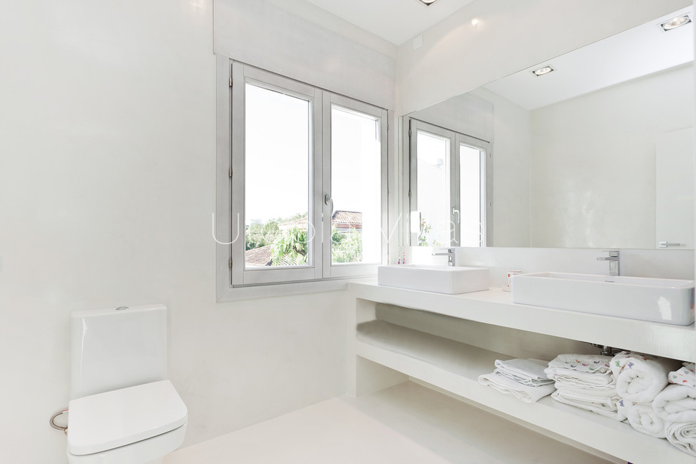 Imagen de cuarto de baño principal mediterráneo con armarios abiertos, puertas de armario blancas, suelo de cemento, lavabo sobreencimera, encimera de cemento y microcemento