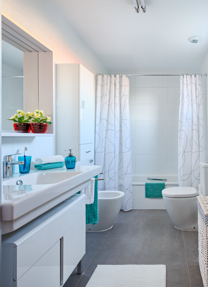 Bild på ett mellanstort vintage en-suite badrum, med släta luckor, vita skåp, ett badkar i en alkov, en dusch/badkar-kombination, en toalettstol med separat cisternkåpa, vita väggar, klinkergolv i keramik, ett integrerad handfat, vit kakel och keramikplattor