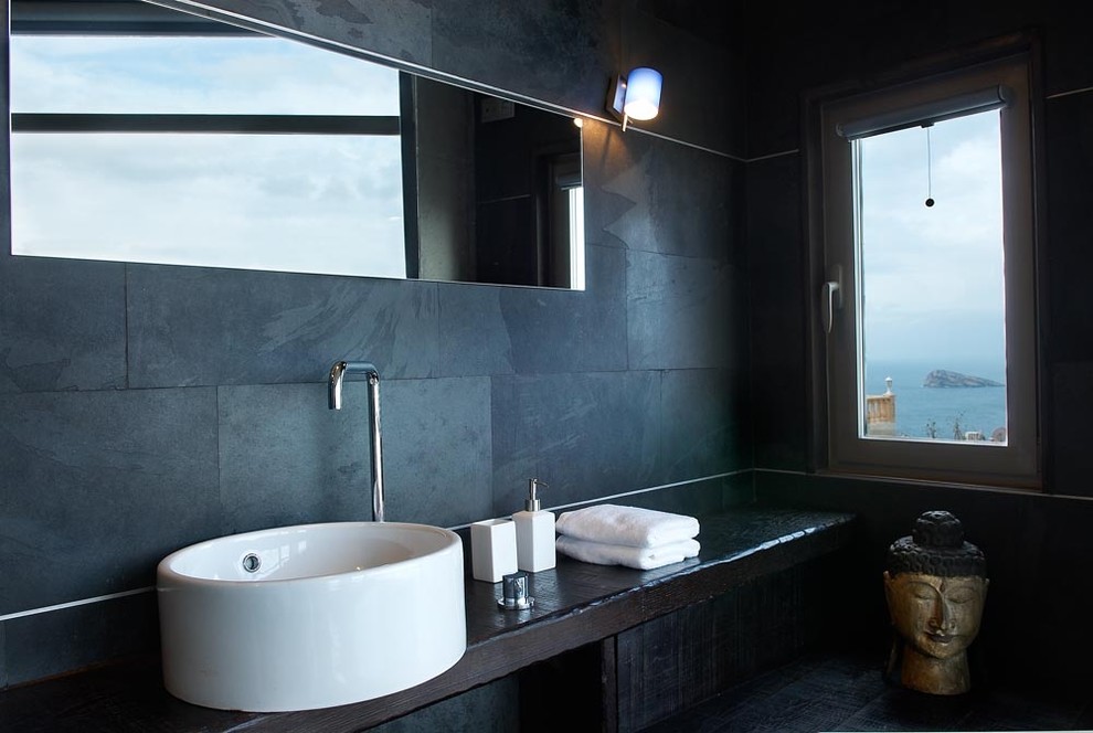 Idéer för ett stort asiatiskt svart en-suite badrum, med luckor med glaspanel, svarta skåp, ett fristående badkar, en kantlös dusch, en toalettstol med separat cisternkåpa, svart kakel, skifferkakel, svarta väggar, mörkt trägolv, ett fristående handfat, träbänkskiva, svart golv och dusch med gångjärnsdörr