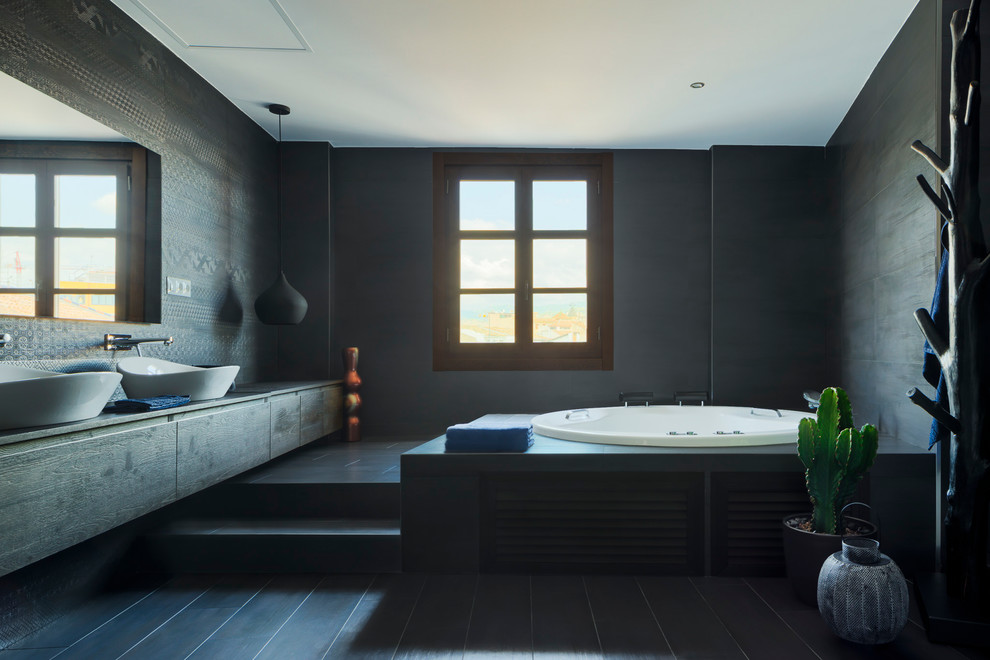 Inredning av ett modernt mycket stort svart svart en-suite badrum, med svarta skåp, en kantlös dusch, svart kakel, keramikplattor, svarta väggar, klinkergolv i keramik, ett fristående handfat, en jacuzzi, träbänkskiva, svart golv och släta luckor