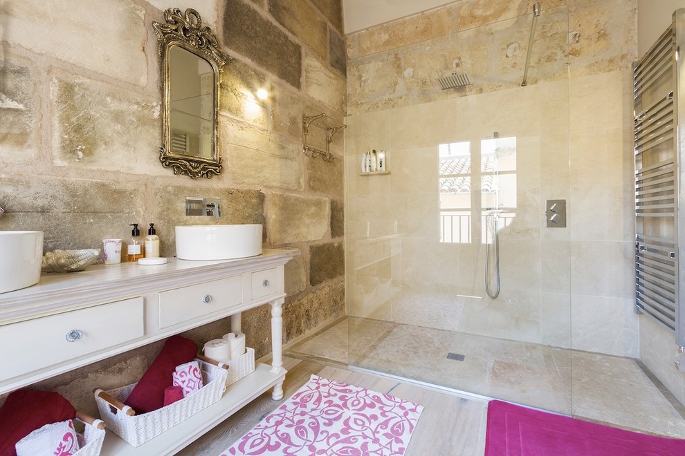 Mittelgroßes Shabby-Look Duschbad mit verzierten Schränken, weißen Schränken, bodengleicher Dusche, beiger Wandfarbe, Aufsatzwaschbecken und Waschtisch aus Holz in Sonstige