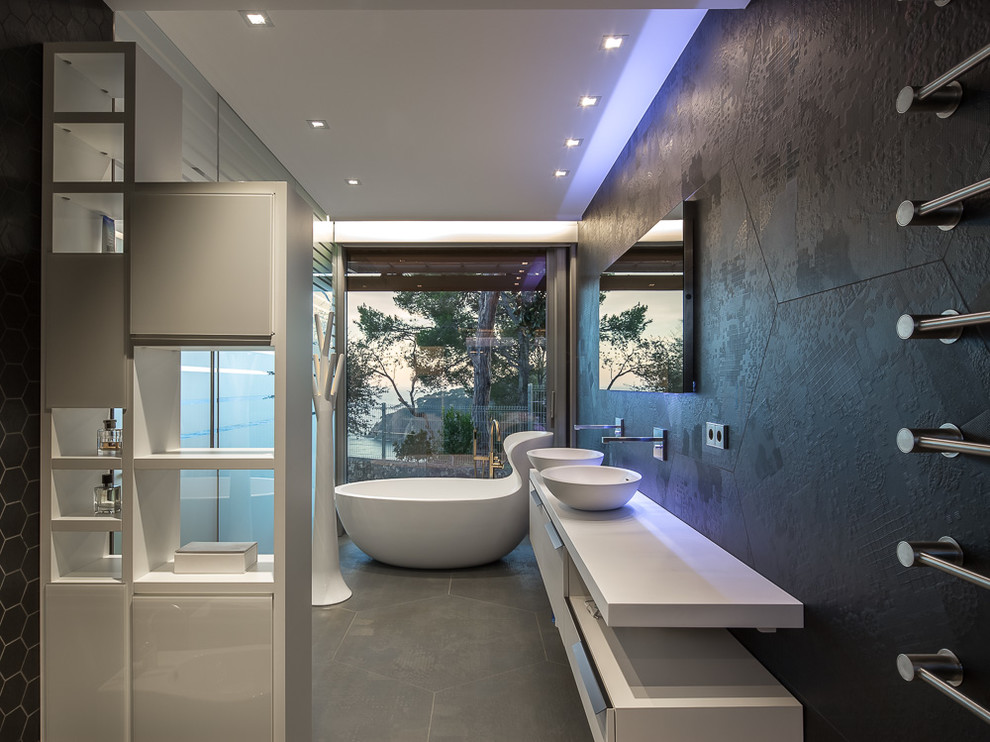 Стильный дизайн: большая главная ванная комната в современном стиле с плоскими фасадами, белыми фасадами, отдельно стоящей ванной, черной плиткой, черными стенами, полом из керамической плитки, настольной раковиной и столешницей из искусственного камня - последний тренд