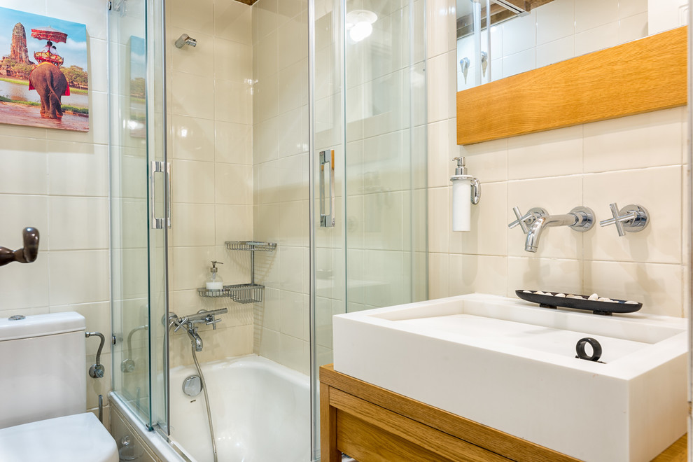 Bild på ett mellanstort minimalistiskt en-suite badrum, med släta luckor, ett hörnbadkar, en dusch/badkar-kombination, en toalettstol med separat cisternkåpa, vita väggar, ett fristående handfat och träbänkskiva