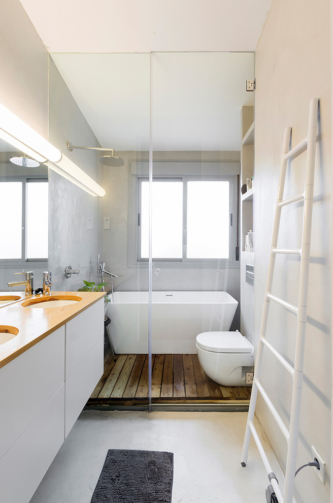 Idées déco pour une petite salle de bain principale scandinave avec un placard à porte plane, des portes de placard blanches, une baignoire indépendante, WC suspendus, un mur gris, un lavabo encastré, un sol gris, une cabine de douche à porte battante et un plan de toilette orange.