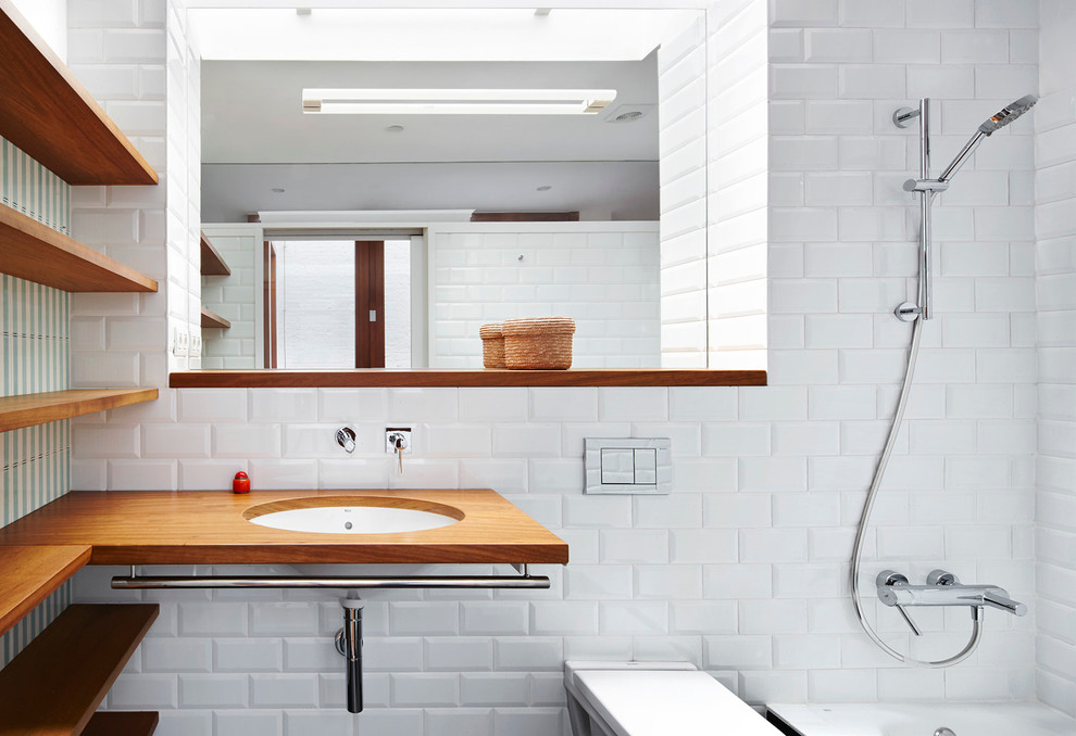 Idéer för mellanstora funkis en-suite badrum, med ett platsbyggt badkar, en dusch/badkar-kombination, en vägghängd toalettstol, vit kakel, keramikplattor, vita väggar, ett nedsänkt handfat, träbänkskiva och med dusch som är öppen
