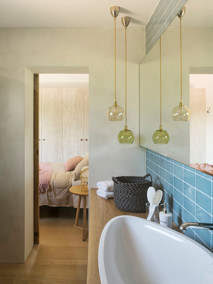 Diseño de cuarto de baño nórdico grande con aseo y ducha, baldosas y/o azulejos azules, paredes blancas, suelo de madera en tonos medios, encimera de madera, suelo marrón y microcemento
