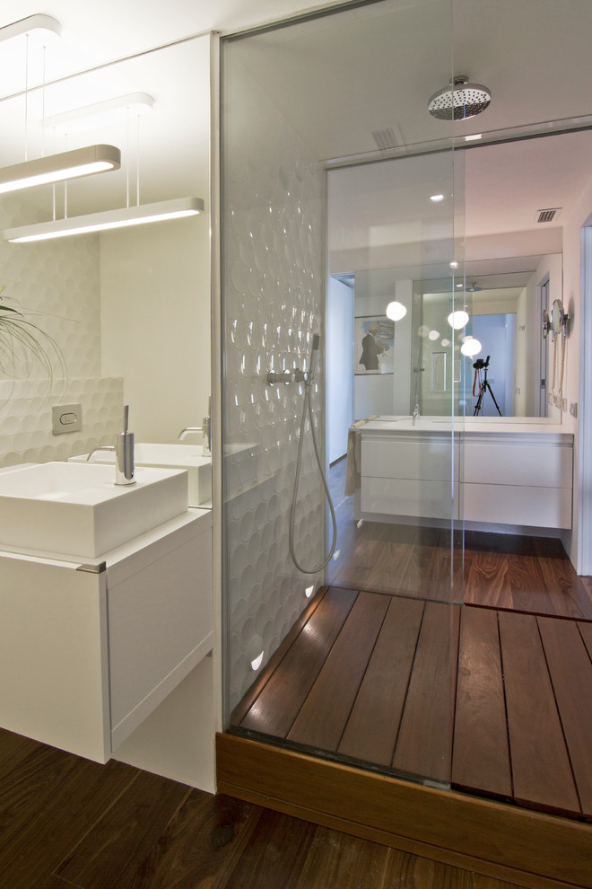 Modelo de cuarto de baño contemporáneo de tamaño medio con armarios con paneles lisos, puertas de armario blancas, ducha abierta, suelo de madera oscura, aseo y ducha y lavabo sobreencimera