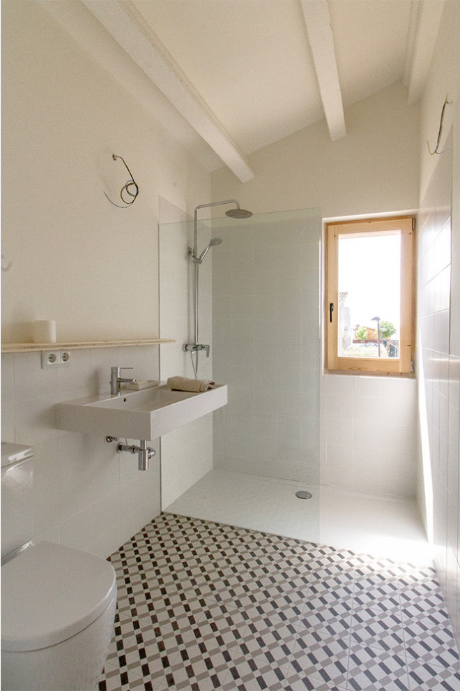 Diseño de cuarto de baño único actual de tamaño medio con sanitario de pared, baldosas y/o azulejos blancos, paredes blancas, aseo y ducha, lavabo suspendido y suelo multicolor