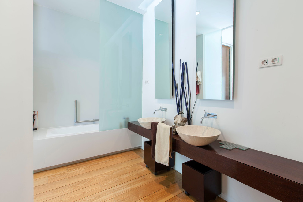 Foto de cuarto de baño actual con combinación de ducha y bañera, paredes blancas, suelo de madera en tonos medios, lavabo sobreencimera, encimera de madera, suelo marrón y encimeras marrones