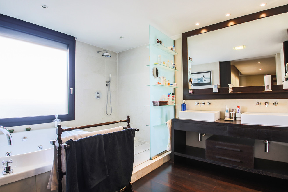 Пример оригинального дизайна: большая главная ванная комната в стиле модернизм с бежевыми фасадами, гидромассажной ванной, угловым душем, бежевыми стенами, темным паркетным полом, раковиной с несколькими смесителями, столешницей из дерева, коричневым полом, открытым душем и коричневой столешницей