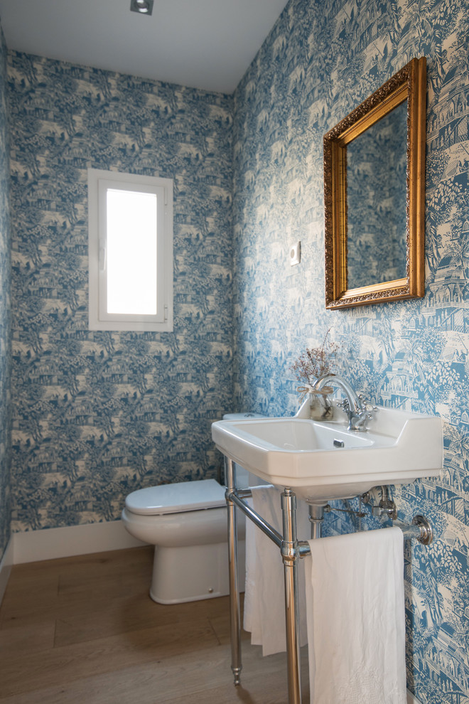 Kleines Eklektisches Badezimmer mit Wandtoilette mit Spülkasten, blauer Wandfarbe, braunem Holzboden, Waschtischkonsole und braunem Boden in Madrid