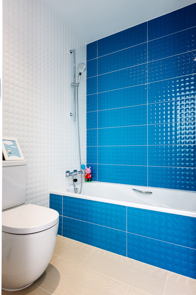 Imagen de cuarto de baño infantil moderno pequeño con bañera encastrada, sanitario de una pieza, baldosas y/o azulejos azules, baldosas y/o azulejos de cerámica, paredes blancas, suelo de pizarra y suelo beige