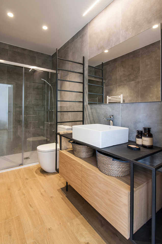 Diseño de cuarto de baño principal contemporáneo con baldosas y/o azulejos grises, baldosas y/o azulejos de porcelana, lavabo sobreencimera, encimera de acero inoxidable y ducha con puerta corredera