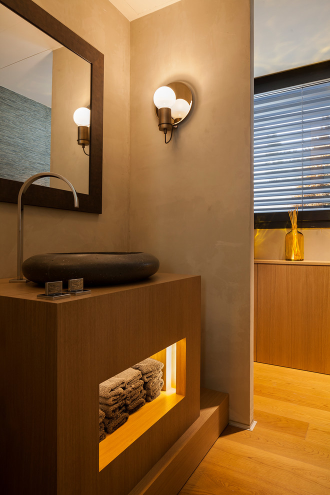 Immagine di una stanza da bagno design con ante in legno scuro, pareti grigie, pavimento in legno massello medio, lavabo a bacinella, top in legno, pavimento marrone e top marrone