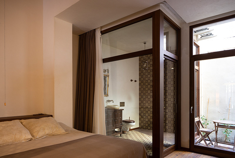 Ejemplo de dormitorio rural de tamaño medio con paredes blancas, suelo de baldosas de cerámica y suelo marrón